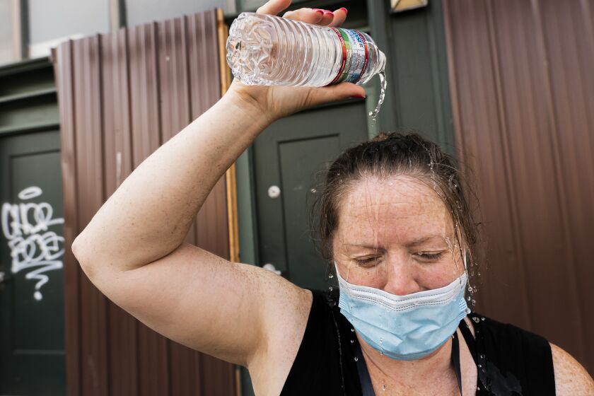 Darlene McApline, an administrative coordinator with Cascadia Behavioral Healthcare's street outreach team, dumps a bottle of water on her head to cool off while loading supplies on Thursday, Aug. 12, 2021, in Portland, Ore. (AP Photo/Nathan Howard)