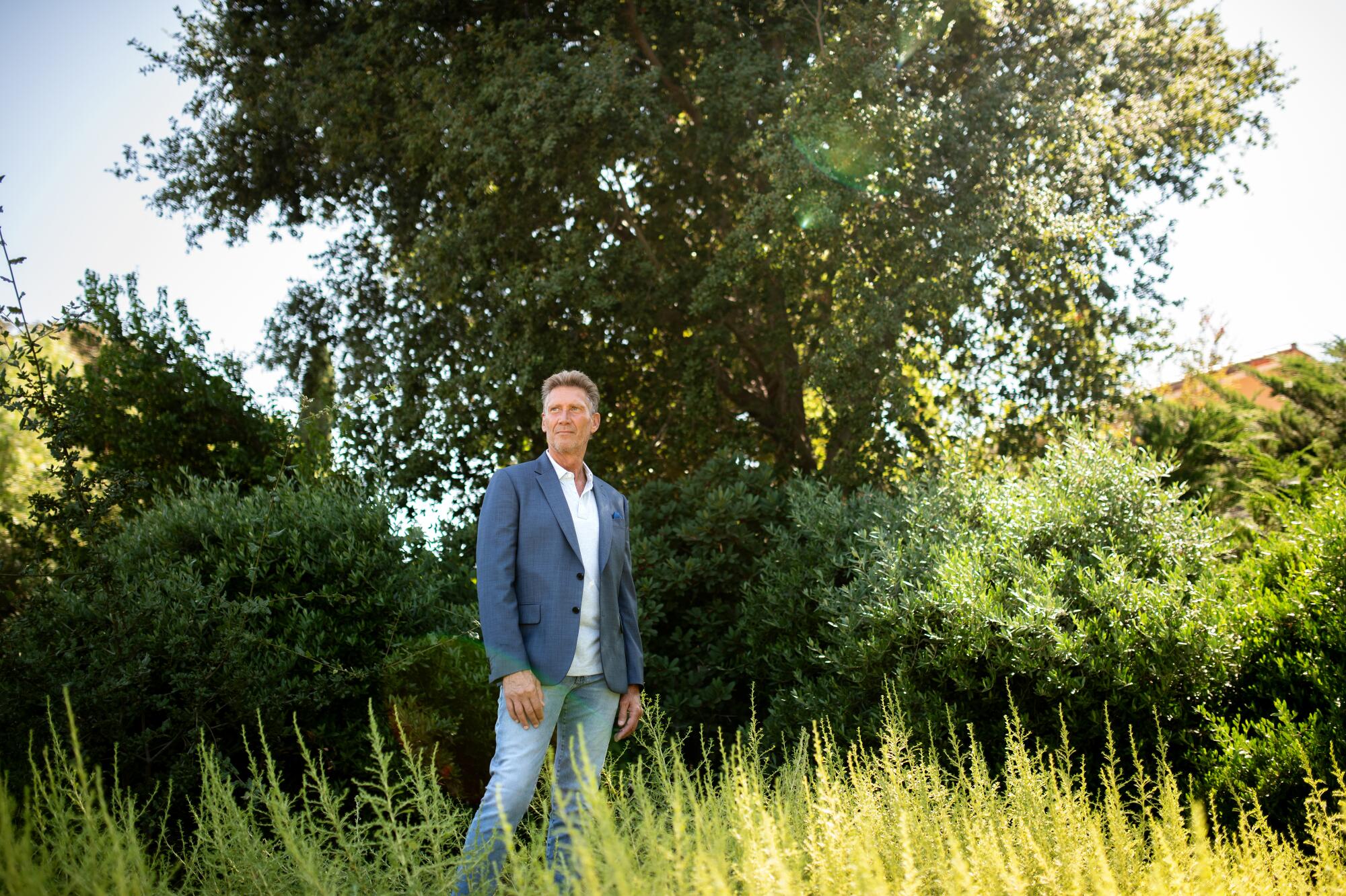 Gerry Turner stands in a field in front of tree.