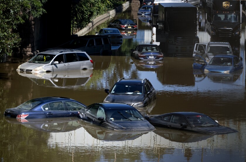 Cars and trucks are shown submerged in high water on a flooded highway