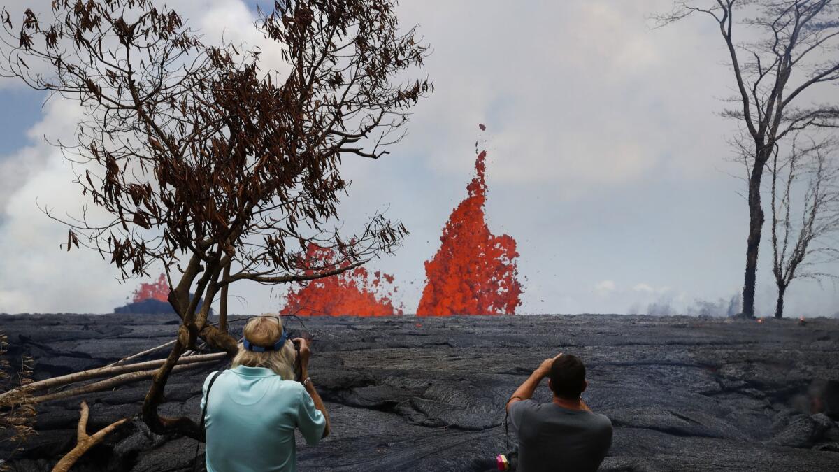 Heath Dalton, right, and Jim Carpenter take pictures as fissures spew lava in the Leilani Estates subdivision near Pahoa, Hawaii.