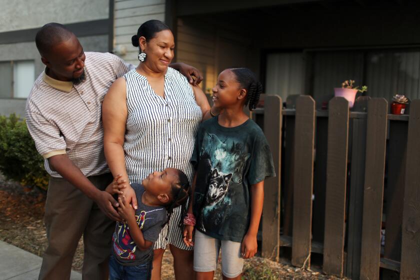 SAN BERNARDINO, CA - AUGUST 21: Terrance Stewart Jr., right, stands for a portrait with his children Terrance the 3rd, 4, and Taylor, 10, and wife Tiffane outside the apartment complex where they have lived since 2018 in Colton on Friday, Aug. 21, 2020 in San Bernardino, CA. Due to crime-free housing policies, ever since Stewart was released from prison on a felony drug charge in 2005 he has struggled to find housing for he and his family. Stewart reflected, "that thing I did in my twenties is not who I am. I bring something positive for the community. (Dania Maxwell / Los Angeles Times)