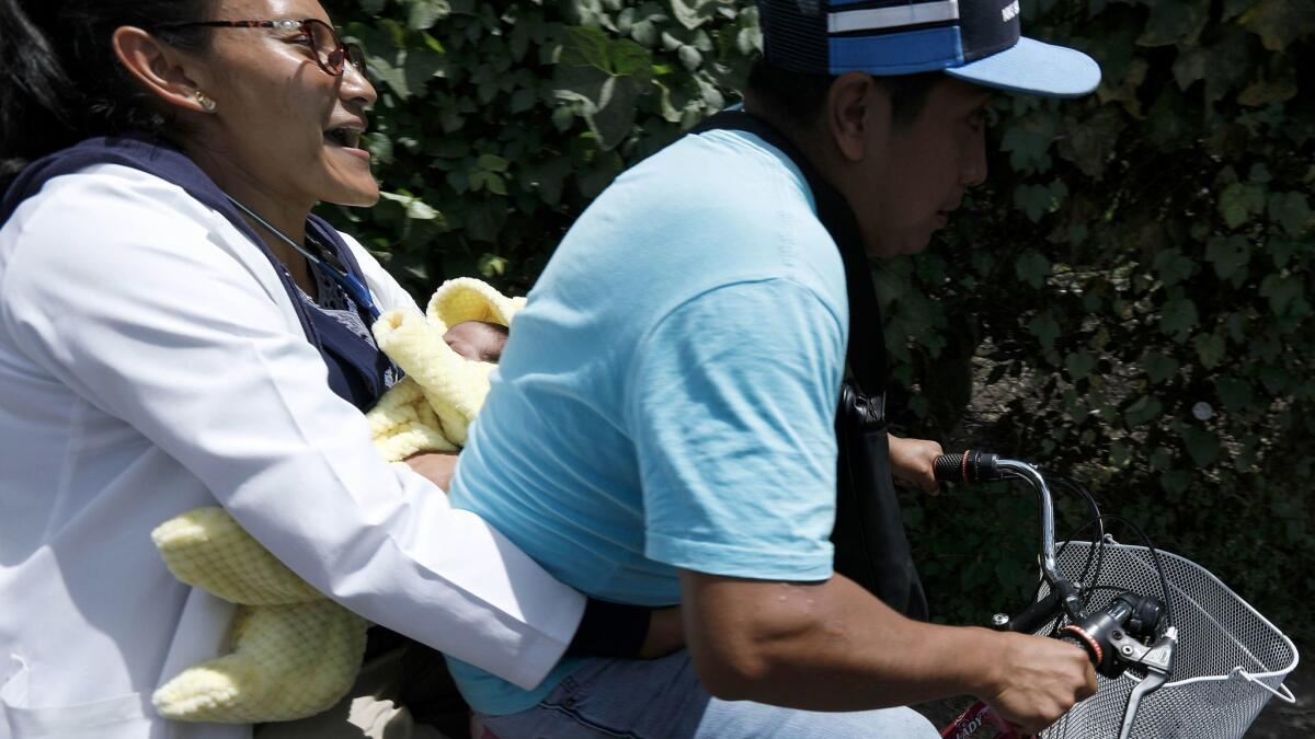 A health worker carrying a dehydrated infant is rushed to medical treatment in the La Cochinta neighborhood of Xochimilco on Friday.