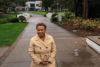 Former U.S. Rep. Barbara Lee stands on a sidewalk at Mills College on a rainy day.