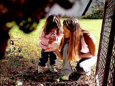 Monique spends time enjoying interaction with her daughter Lyla looking for bugs in the park.