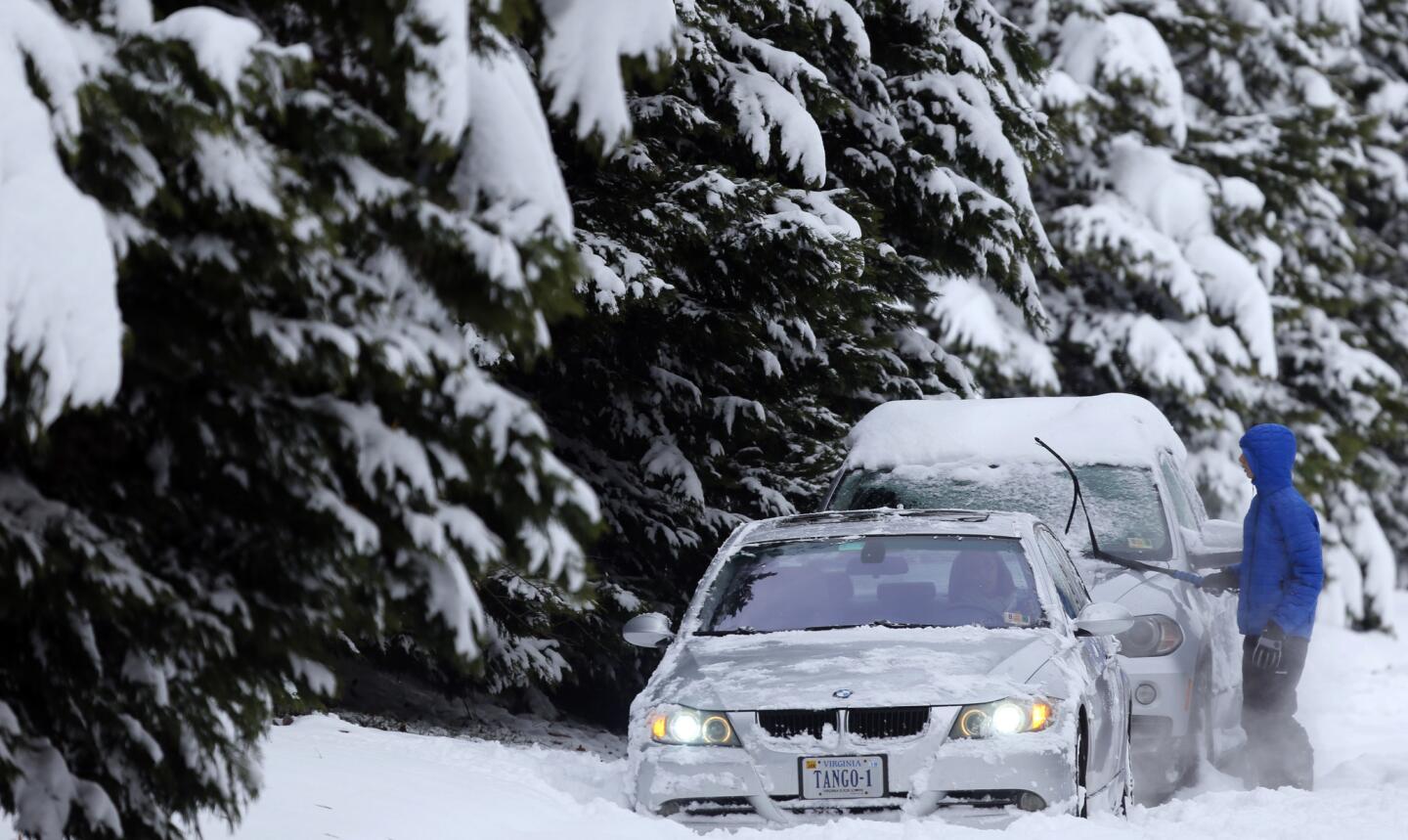 A motorist cleans snow off cars in Richmond, Va., on Monday.