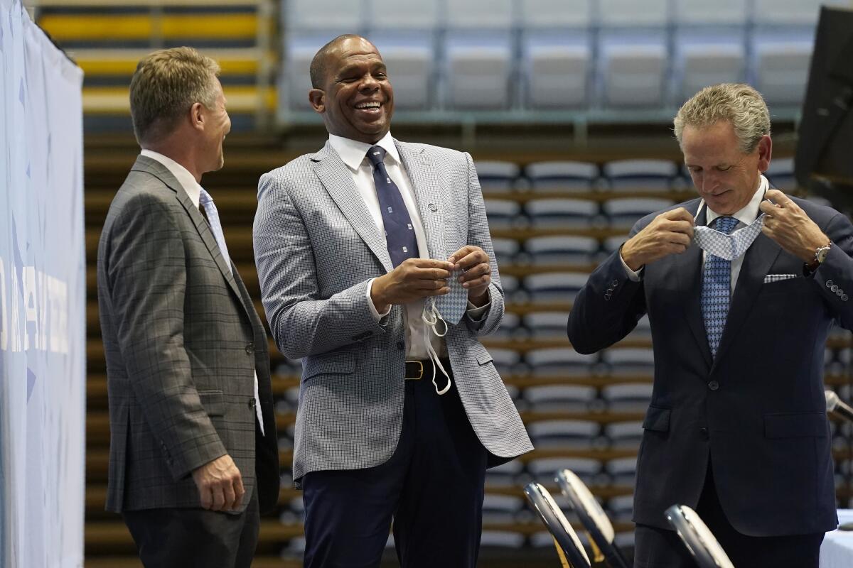North Carolina head coach Hubert Davis, center, laughs with chancellor Kevin Guskiewicz, left, and athletic director Bubba Cunningham following a news conference at the University of North Carolina in Chapel Hill, N.C., Tuesday, April 6, 2021. Davis was named the Tar Heels new NCAA men's basketball coach following the retirement of Roy Williams. (AP Photo/Gerry Broome)