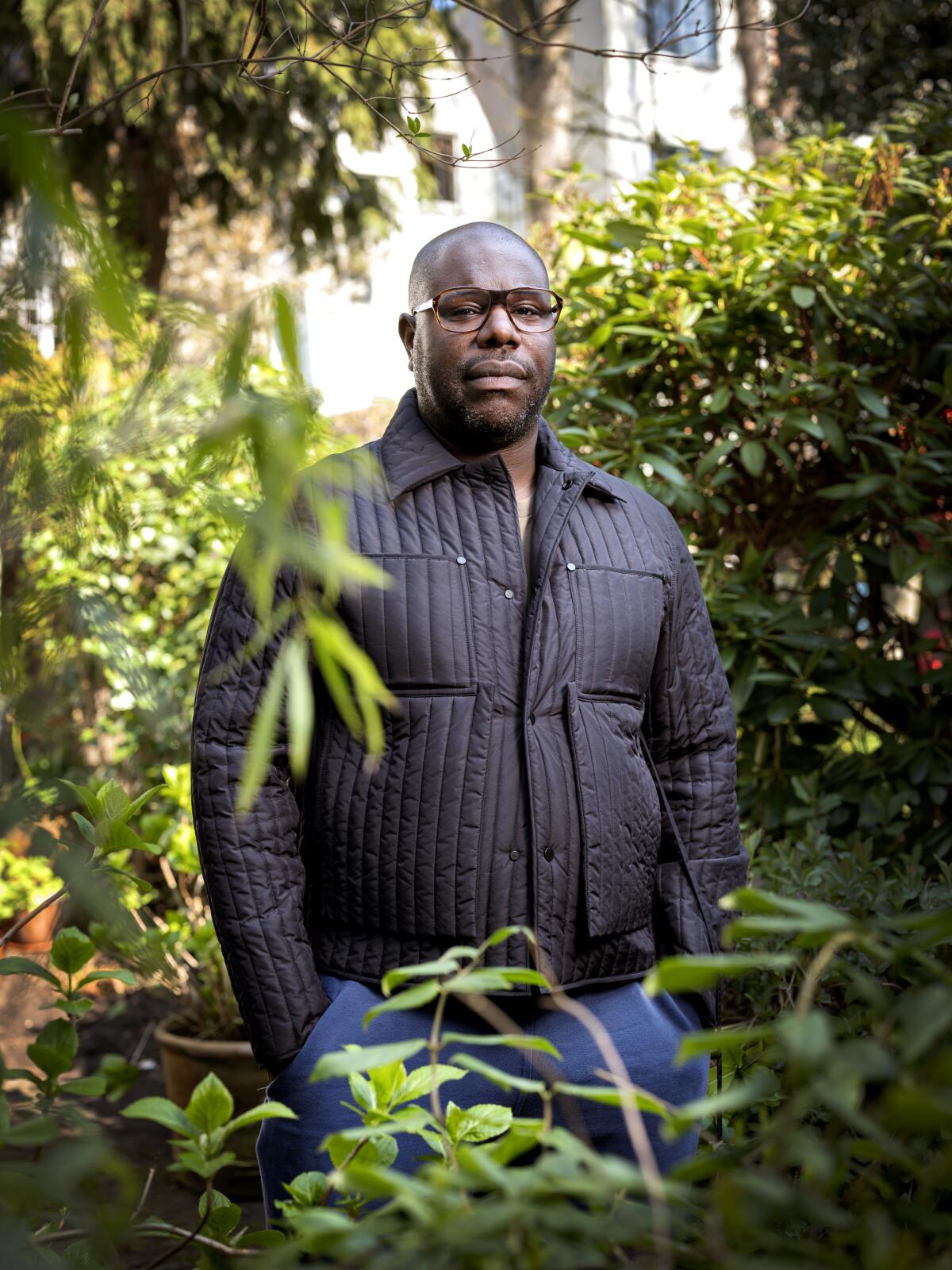 Filmmaker Steve McQueen stands in a garden.