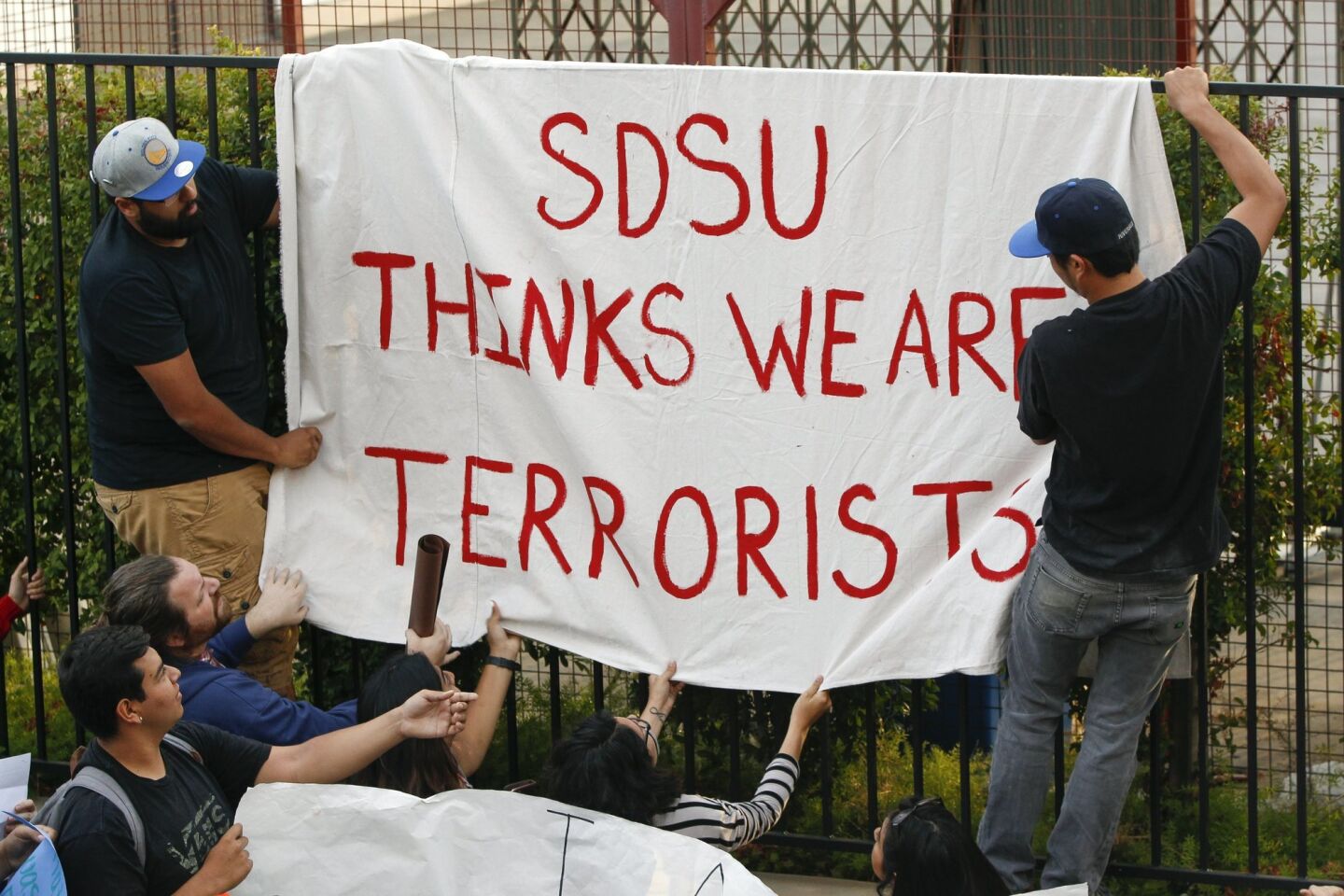 San Diego State students put up a sign as other students surround the SDSU president.