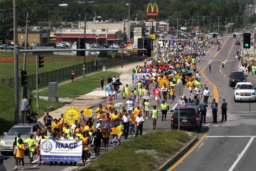 Members of the St. Louis chapters of the NAACP and the National Urban League march on West Florissant Avenue in Ferguson, Mo.