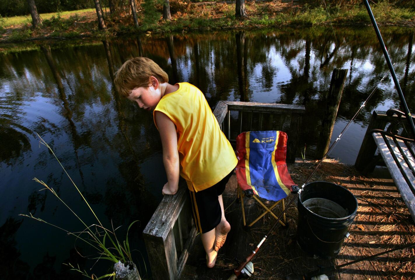 Dillion Chancey looks for fish in the dark waters of a pond at his aunt's home, where he is staying while his parents try to put their lives back together after Hurricane Katrina. Dillion and his parents, Bobby Chancey and Sarah Fairchild, were floating in the hurricane waters for 12 hours when the storm hit their home in Biloxi, Miss.