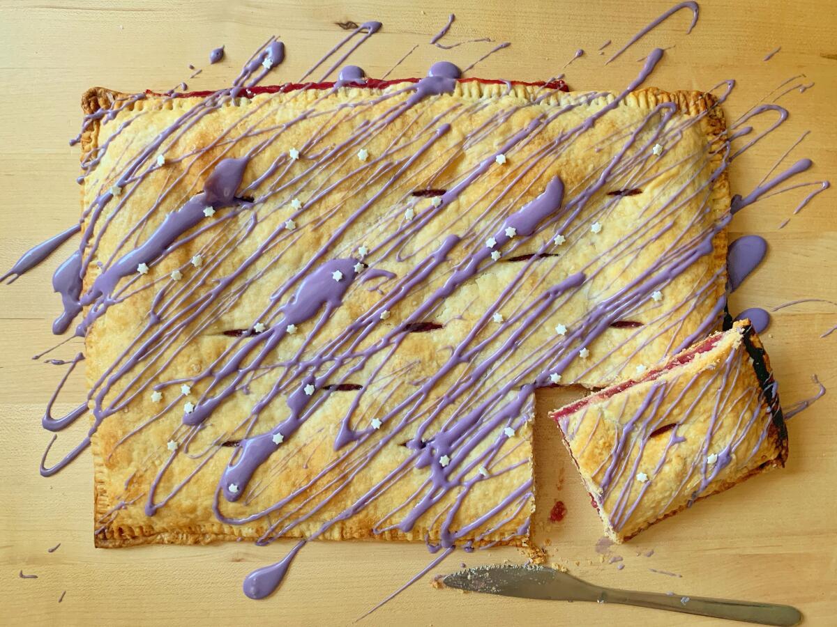 A rectangular pastry with a corner piece cut out, all drizzled with purple icing