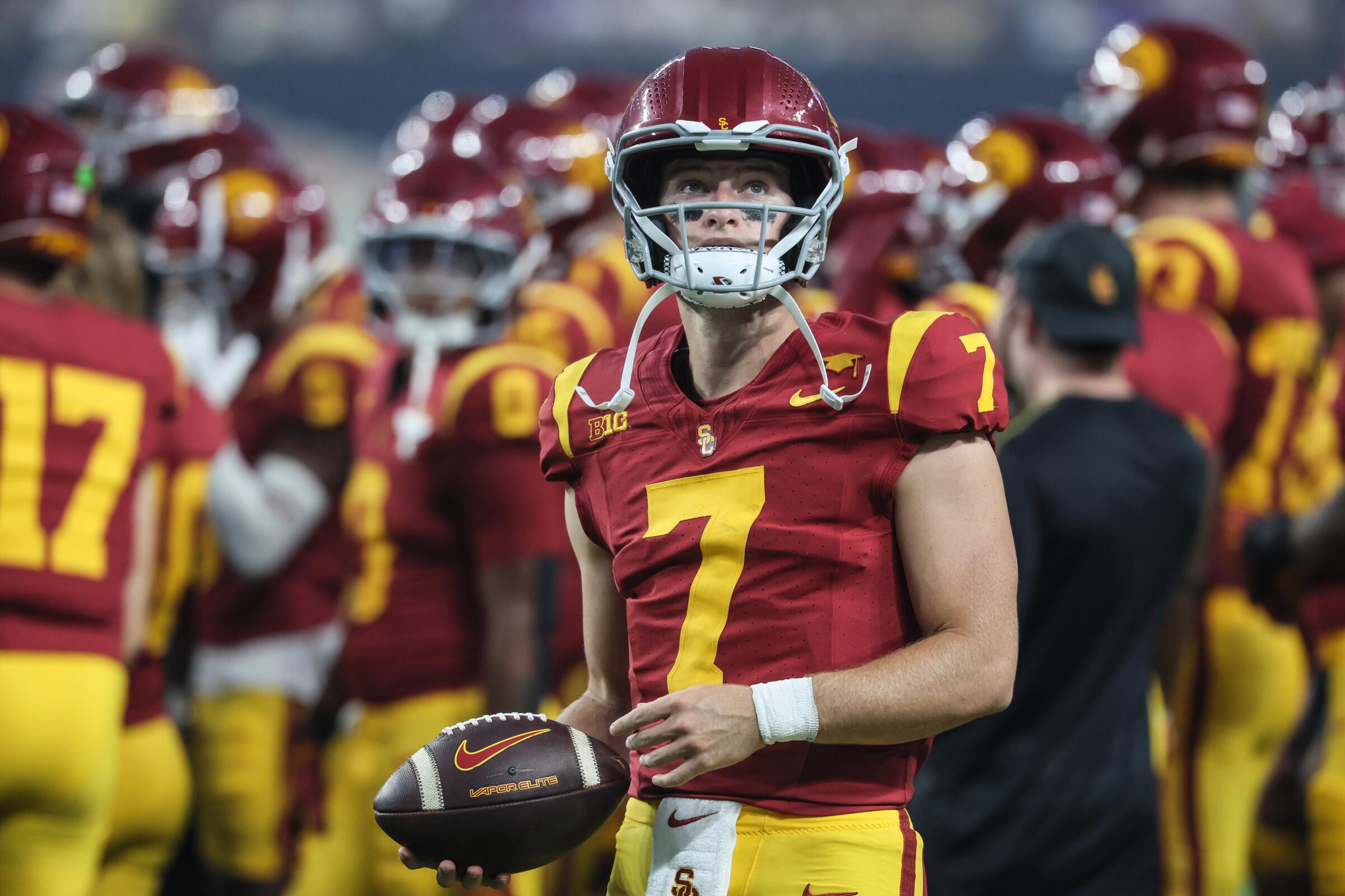 USC quarterback Miller Moss holds a football and up toward the sideline during a game against LSU in Las Vegas