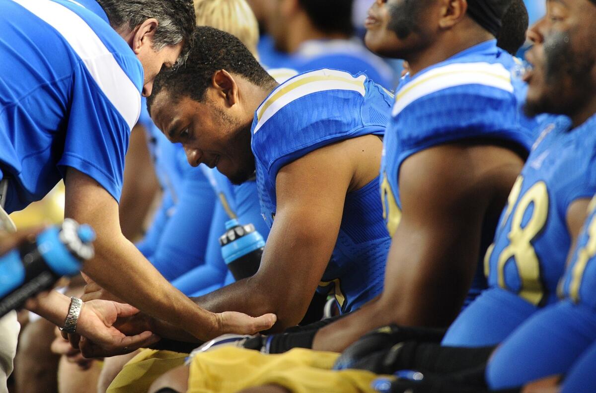 UCLA quarterback Brett Hundley has his left elbow checked out after suffering an injury in the first quarter.