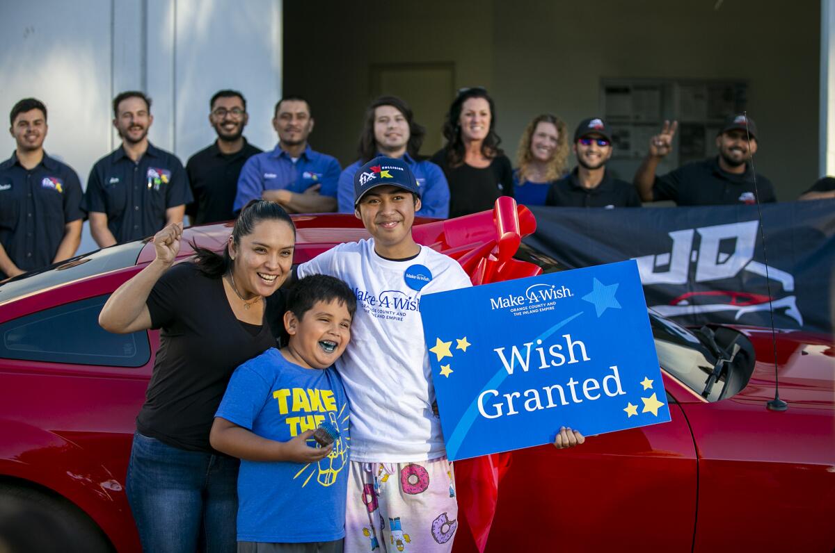 Moses Suarez, 20, mom Hortencia Zamora and brother Jake Zamora pose in front of his refurbished Ford Mustang Friday.