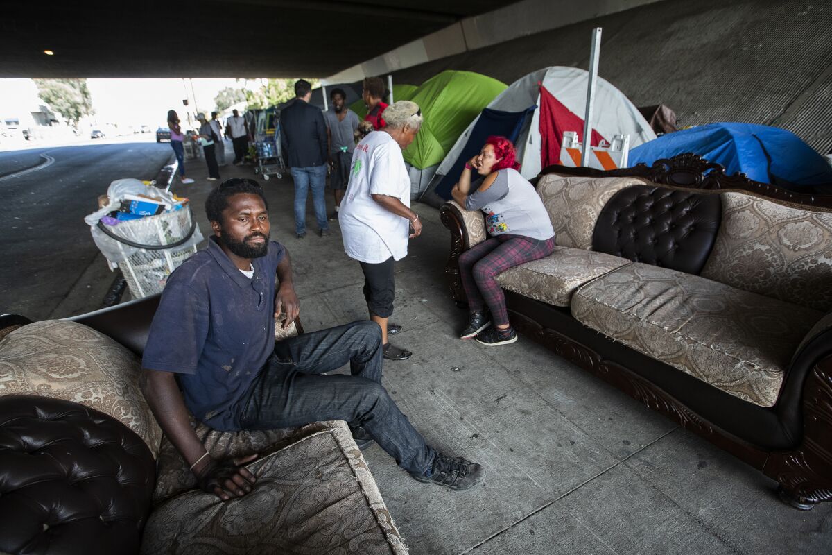 Dennis Karimi, 30, sits on a couch that also serves as his bed at the homeless encampment in Pacoima.