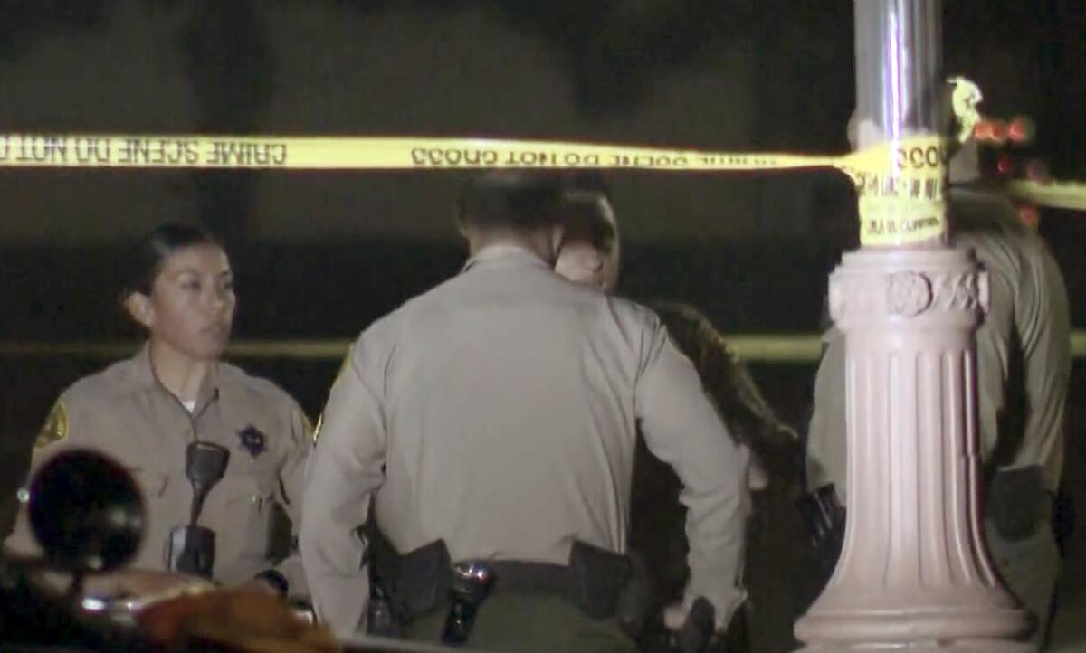 Sheriff’s deputies stand next to a lamppost with crime scene tape