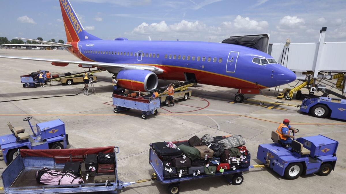 Baggage carts are towed to a Southwest Airlines jet at Bill and Hillary Clinton National Airport in Little Rock, Ark. Southwest Airlines announced plans to improve its Wi-Fi service next year.