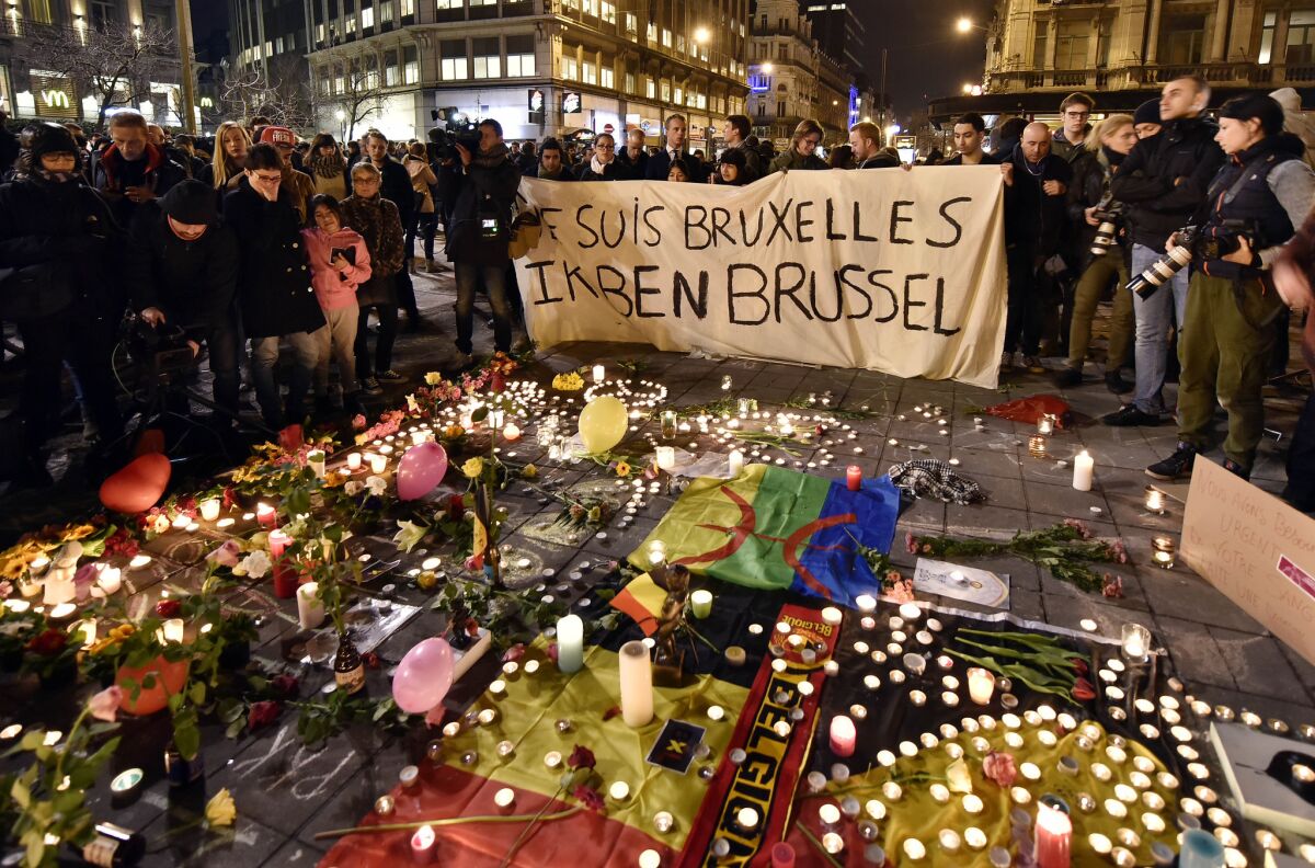 People holding a banner reading "I am Brussels" behind flowers and candles to mourn for the victims at Place de la Bourse in the center of Brussels on March 22.