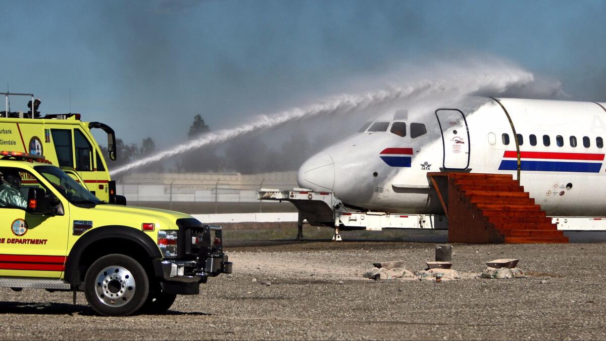 A Burbank Airport Fire Department truck sprays water on an old airplane fuselage after a mock explosion during the a training exercise on Tuesday, March 24, 2015.