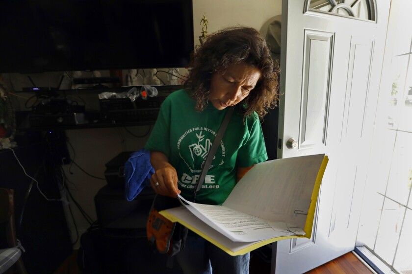 A woman in a green sweatshirt looks over papers