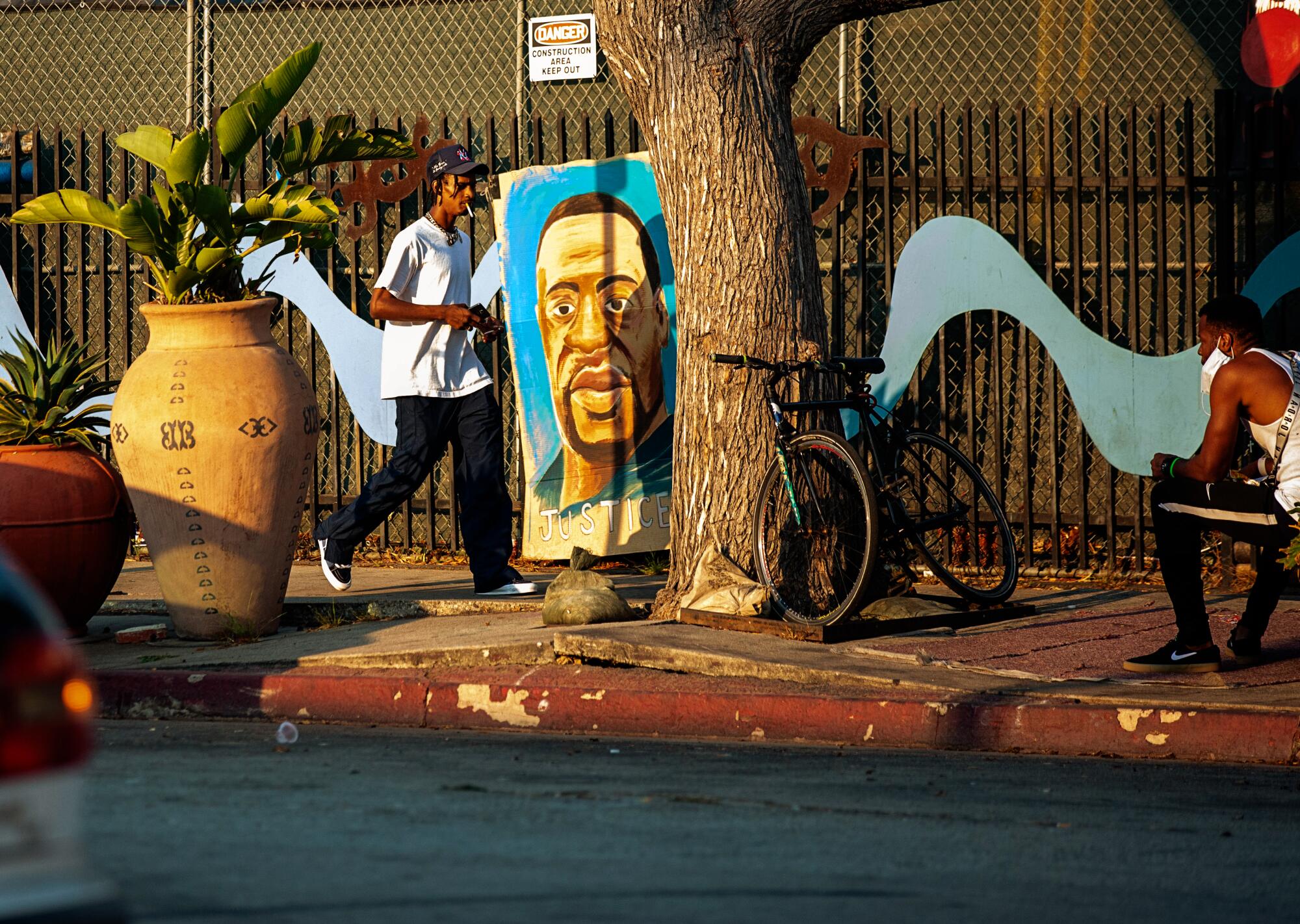 A man walks by a painting of George Floyd in Leimert Park..