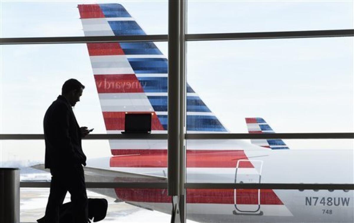 ARCHIVO - En esta fotografía de archivo del 25 de enero de 2016, un pasajero habla por teléfono mientrsa un avión de American Airlines permanece estacionado en el Aeropuerto Nacional Ronald Reagan de Washington. (AP foto/Susan Walsh, archivo)