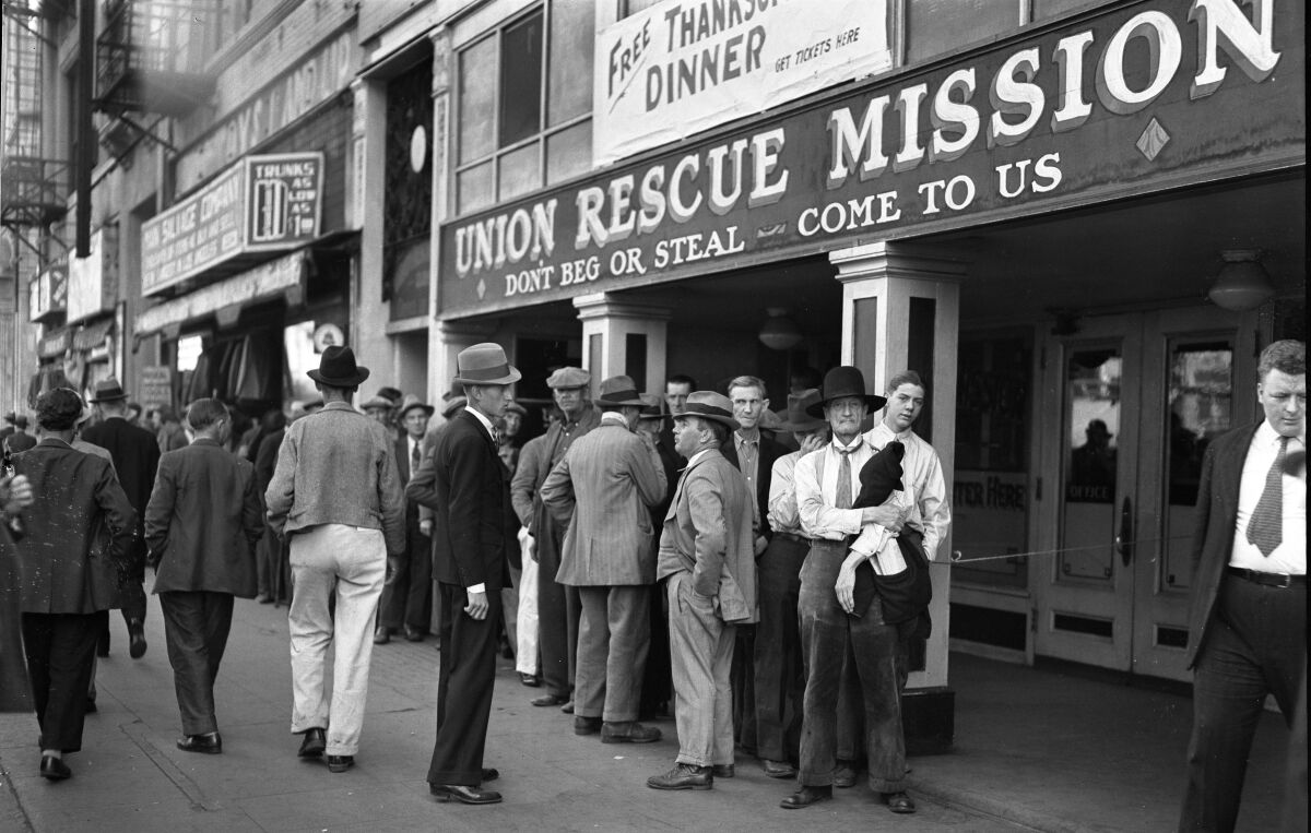 Men, mostly in hats and ties, line up outside a building whose sign includes "Don't beg or steal. Come to us."