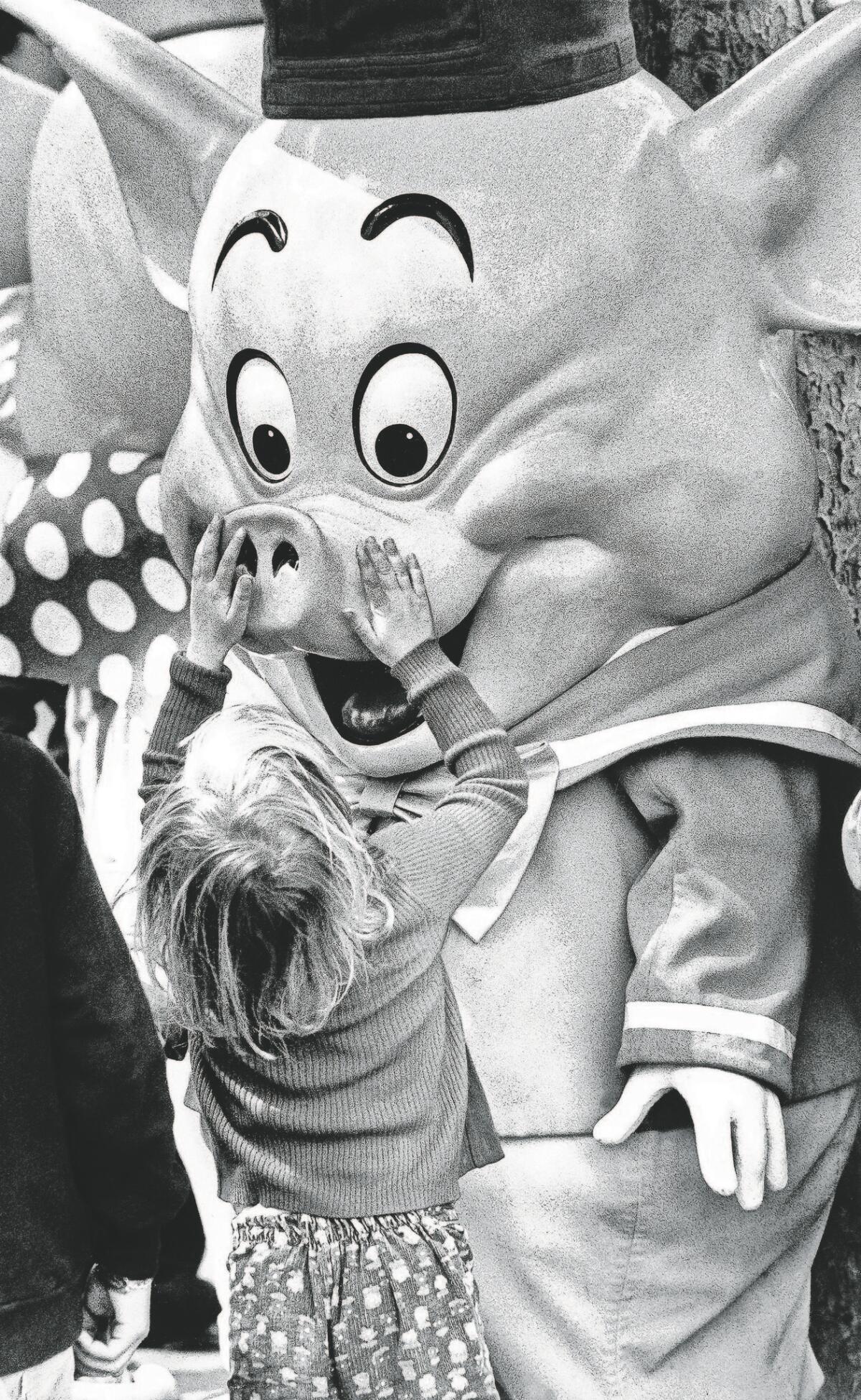 A child visiting Disneyland lovingly touches one of the "Three Little Pigs" costumed characters, a popular attraction at Disneyland, in 1977.