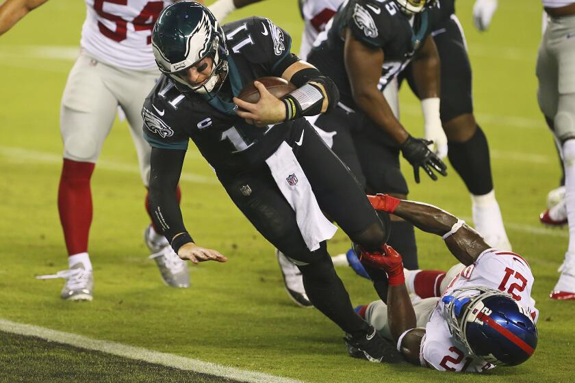 Philadelphia Eagles' Carson Wentz (11) as tackled New York Giants' Gabriel Peppers (21) as he scores a rushing touchdown during the first half of an NFL football game, Thursday, Oct. 22, 2020, in Philadelphia. (AP Photo/Rich Schultz)