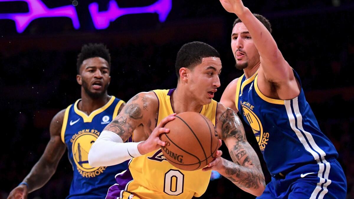 Lakers' Kyle Kuzma tries to get past Golden State's Klay Thompson, right, and Jordan Bell on Dec. 18 at Staples Center.