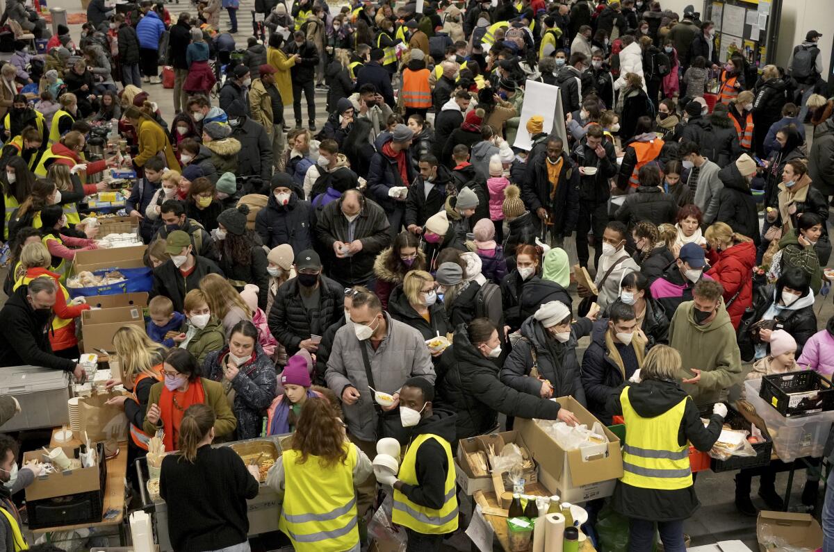 FILE - Ukrainian refugees queue for food in the welcome area after their arrival at the main train station in Berlin, Germany, March 8, 2022. German government pledged Tuesday to provide more support to cities and towns struggling to house more than 1.1 million refugees who have arrived in the country this year mostly from war-torn Ukraine but also other countries such as Syria and Afghanistan. (AP Photo/Michael Sohn, File)