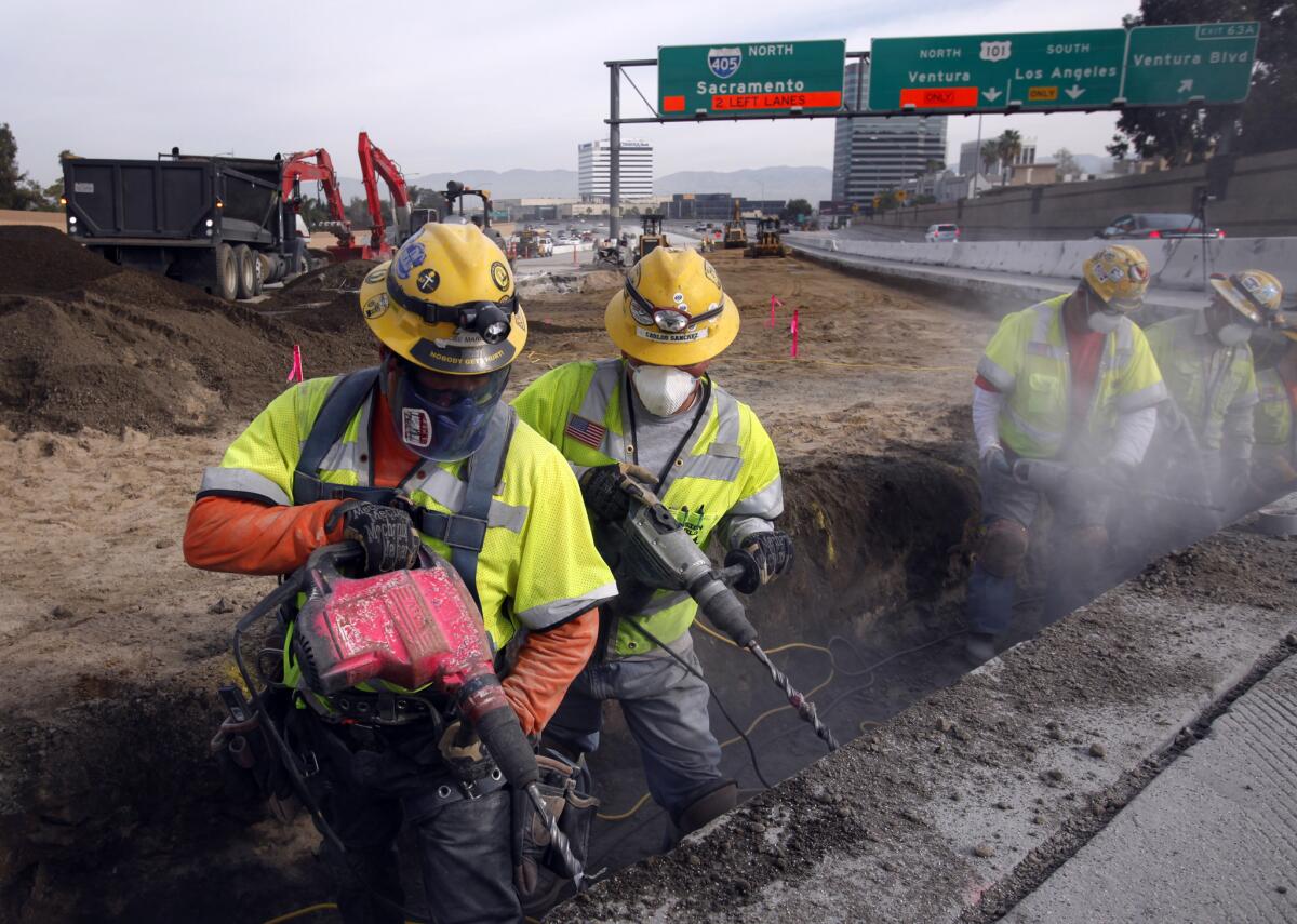 Workers drill holes into the concrete Saturday as they rebuild the pavement on the 405 Freeway, just south of the Ventura Boulevard offramp in Los Angeles.