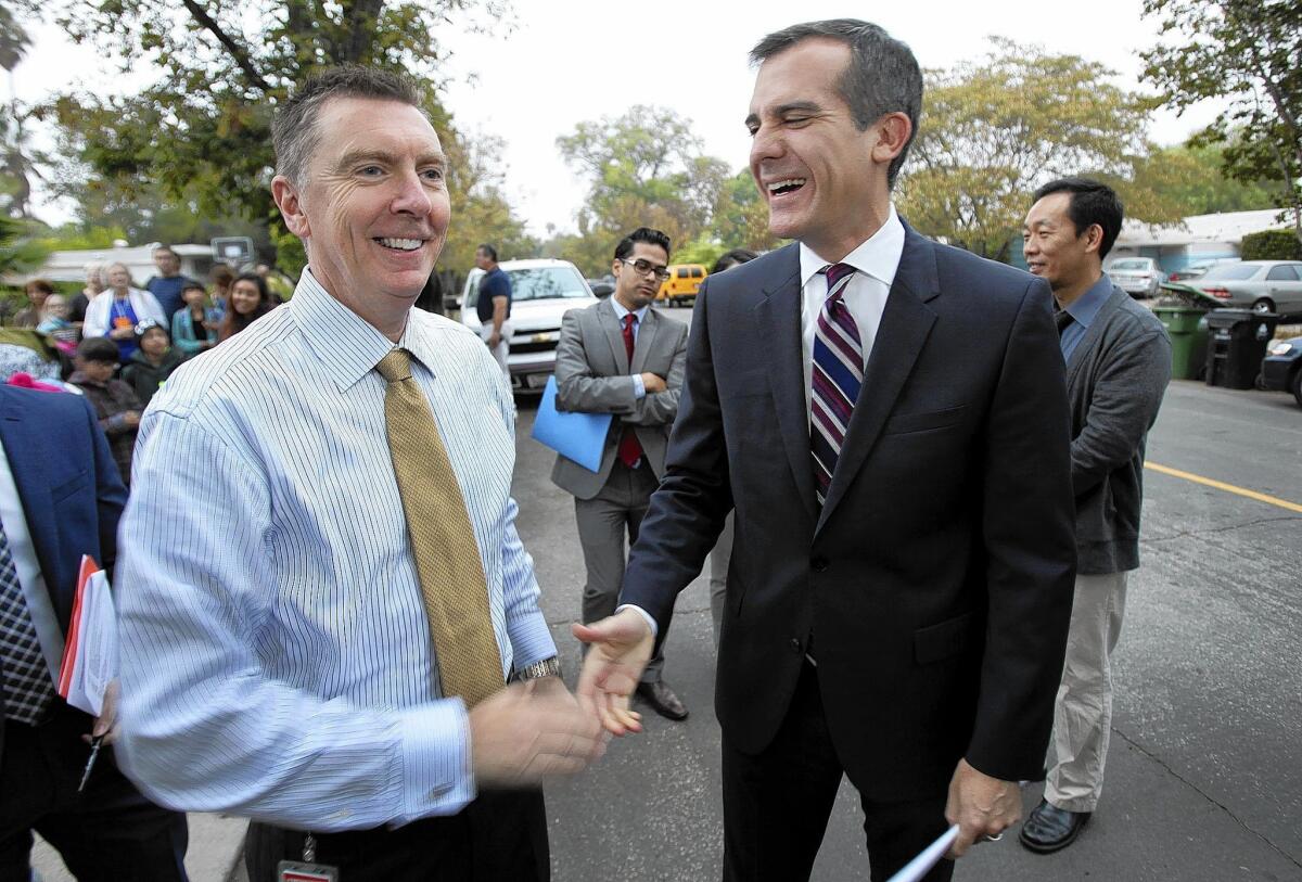 Los Angeles Unified School District Supt. John Deasy, left, greets Mayor Eric Garcetti, right, during a school event in October. The Board of Education approved a modified contract for Deasy last week.