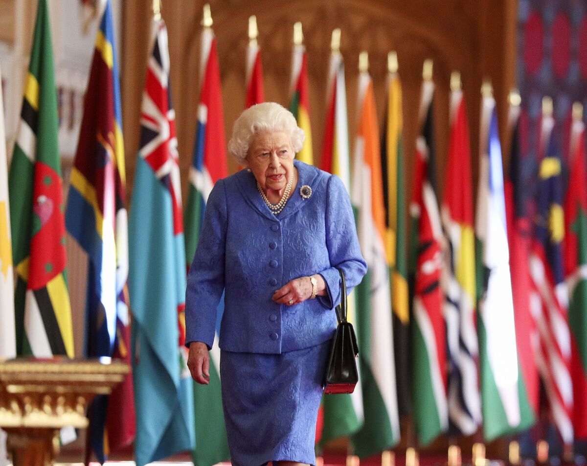 Britain's Queen Elizabeth II walks past Commonwealth flags in St George's Hall at Windsor Castle, England to mark Commonwealth Day in this image that was issued on Saturday March 6, 2021. The timing couldn’t be worse for the Queen's grandson Harry and his wife Meghan. The Duke and Duchess of Sussex will finally get the chance to tell the story behind their departure from royal duties directly to the public on Sunday, when their two-hour interview with Oprah Winfrey is broadcast. (Steve Parsons/Pool via AP)