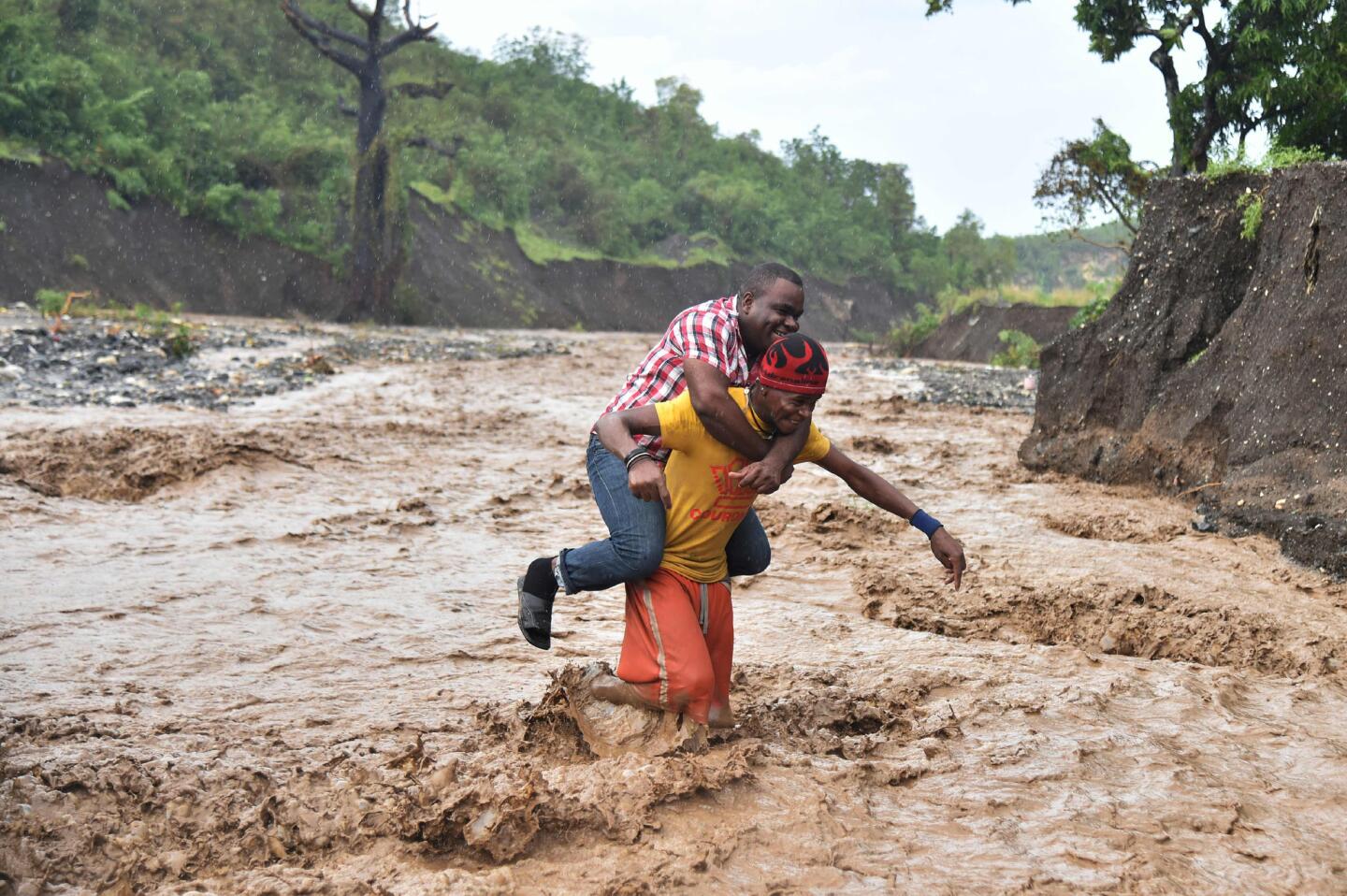 A man is carried across the river La Digue in Petit Goave where the bridge collapsed during the rains of the Hurricane Matthew, southwest of Port-au-Prince, Haiti, on Oct. 5, 2016.