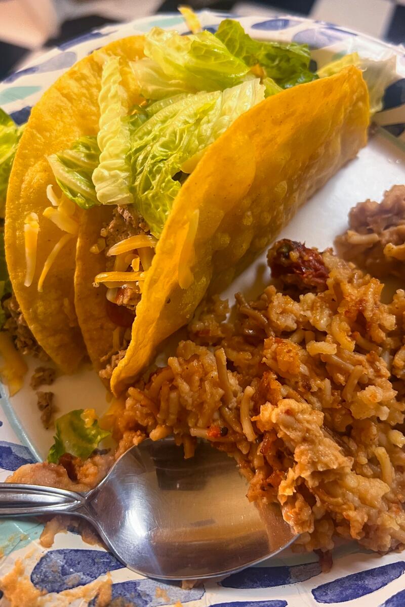 A plate with two tacos, Mexican rice and refried beans