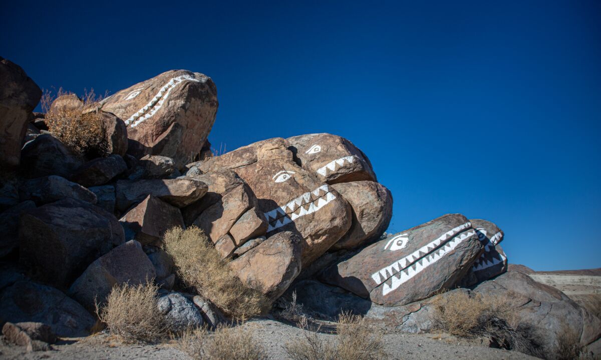 Several large rocks painted with eyes and teeth to resemble fish in profile.