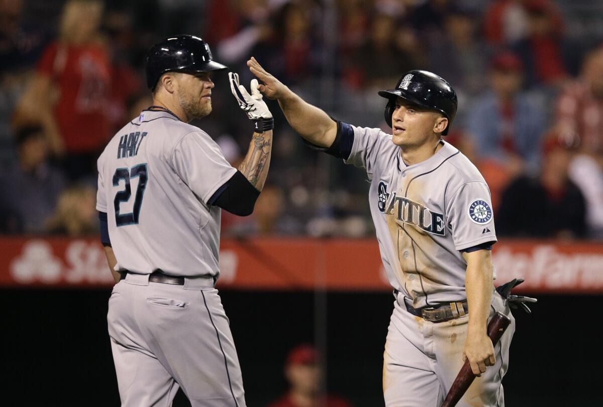 Seattle third baseman Kyle Seager, right, is greeted by designated hitter Corey Hart after scoring on a double by first baseman Logan Morrison in the 12th inning. The Angels lost to the Mariners, 3-2, in 12 innings.