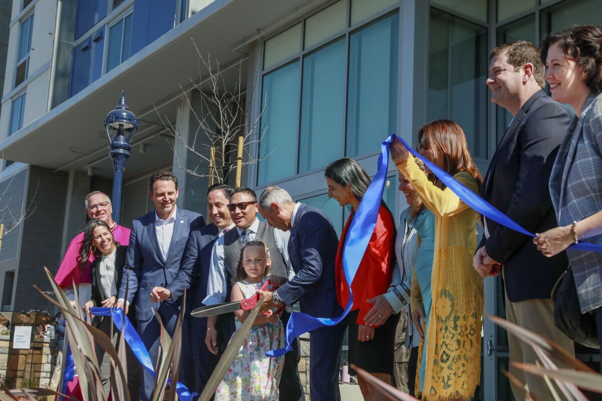 Deacon Jim Vargas, with help from 7-year-old Abigail Fish, cuts the ribbon to Saint Teresa of Calcutta Villa on Thursday.
