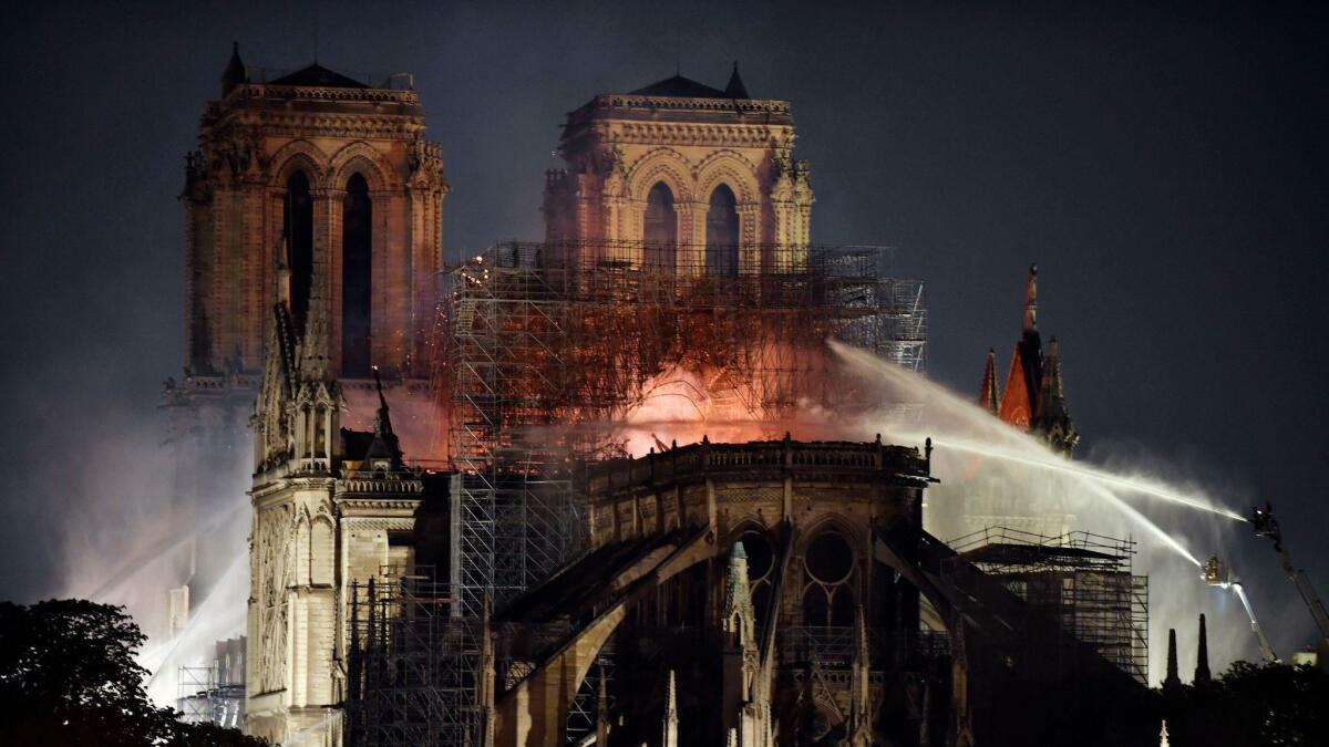 French firefighters spray water to extinguish flames burning the roof of Notre Dame Cathedral in Paris on April 15.