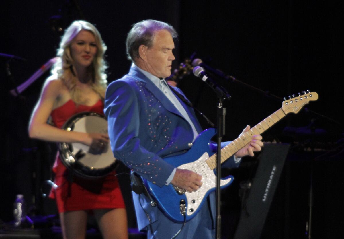 Glen Campbell shown during the Hollywood Bowl stop on his 2012 Goodbye Tour, with daughter Ashley Campbell in the background. A new song "I'm Not Gonna Miss You" charts the toll Alzheimer's has taken on the Grammy Award-winning singer, guitarist and songwriter.