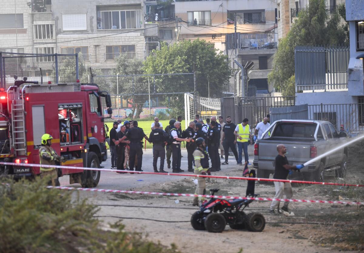 Israeli police officers and firefighters work at the site of a rocket attack. 