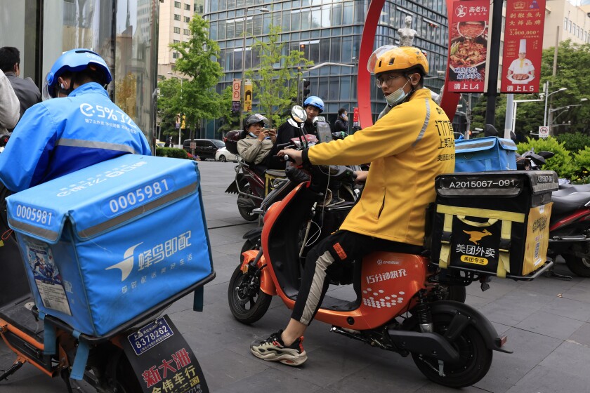 FILE - In this April 21, 2021, file photo, a Meituan delivery man in yellow goes on his rounds in Shanghai. Shares in Meituan, China’s largest food delivery platform, have tumbled Tuesday, May 11, 2021 after its CEO posted -and then deleted - an ancient poem in a move widely seen as criticism of the Chinese government. Authorities are investigating the company over allegations of anti-monopolistic behavior, part of a wider crackdown on technology companies. (AP Photo/Ng Han Guan, File)