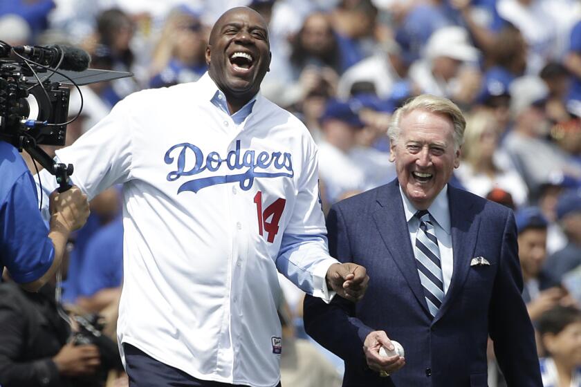 Los Angeles Dodgers part-owner Magic Johnson, center left, and broadcaster Vin Scully laugh as they walk on the field before a baseball game against the San Francisco Giants, Friday, April 4, 2014, in Los Angeles. (AP Photo/Jae C. Hong)