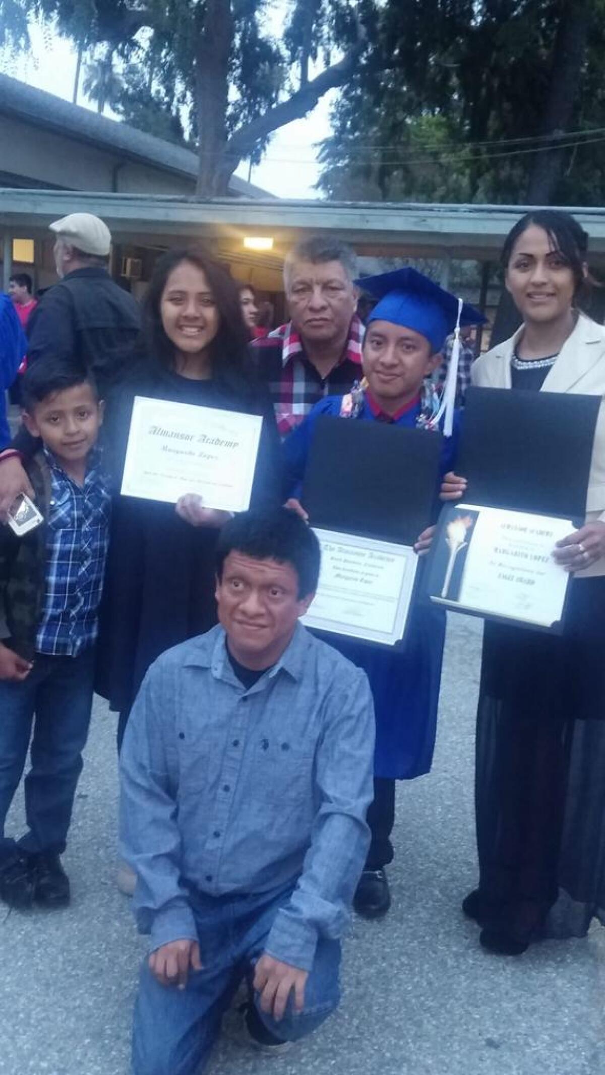 A high school graduate poses with his family
