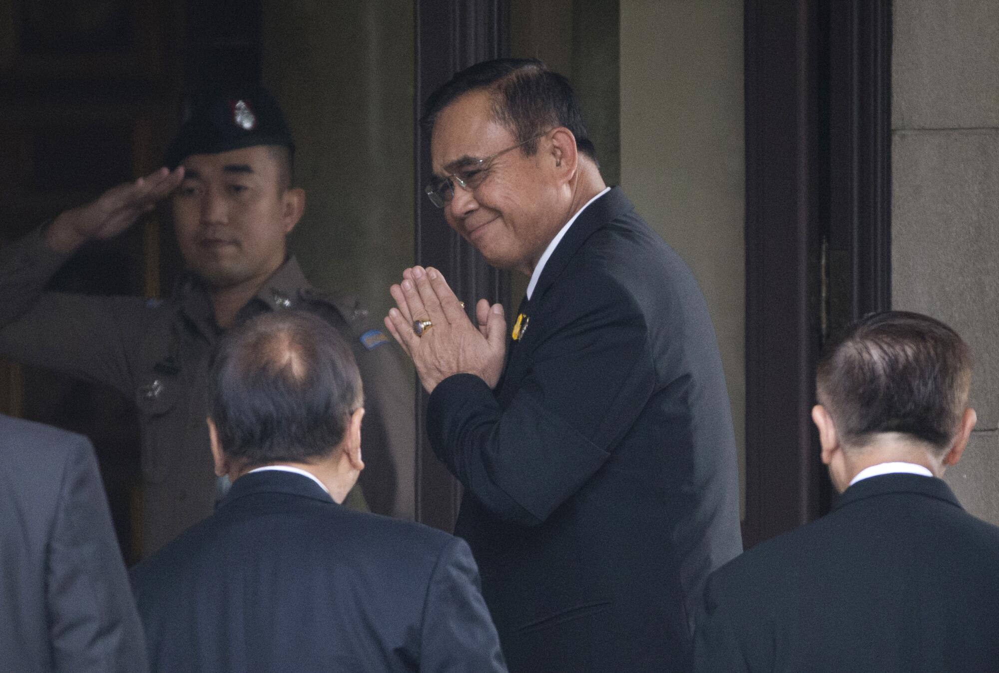 Thailand's Prime Minister Prayuth Chan-ocha arrives at a building guarded by a man in uniform 