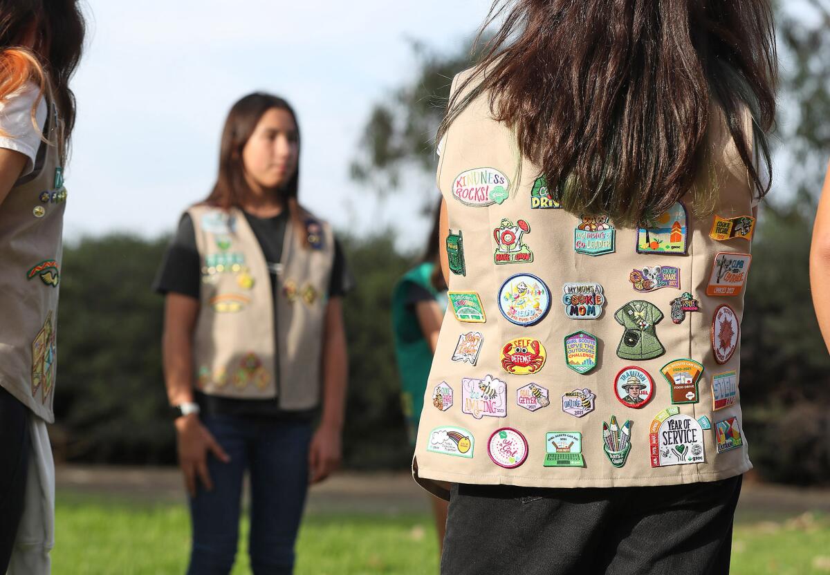 Girls standing with their Girl Scout vests on at the park