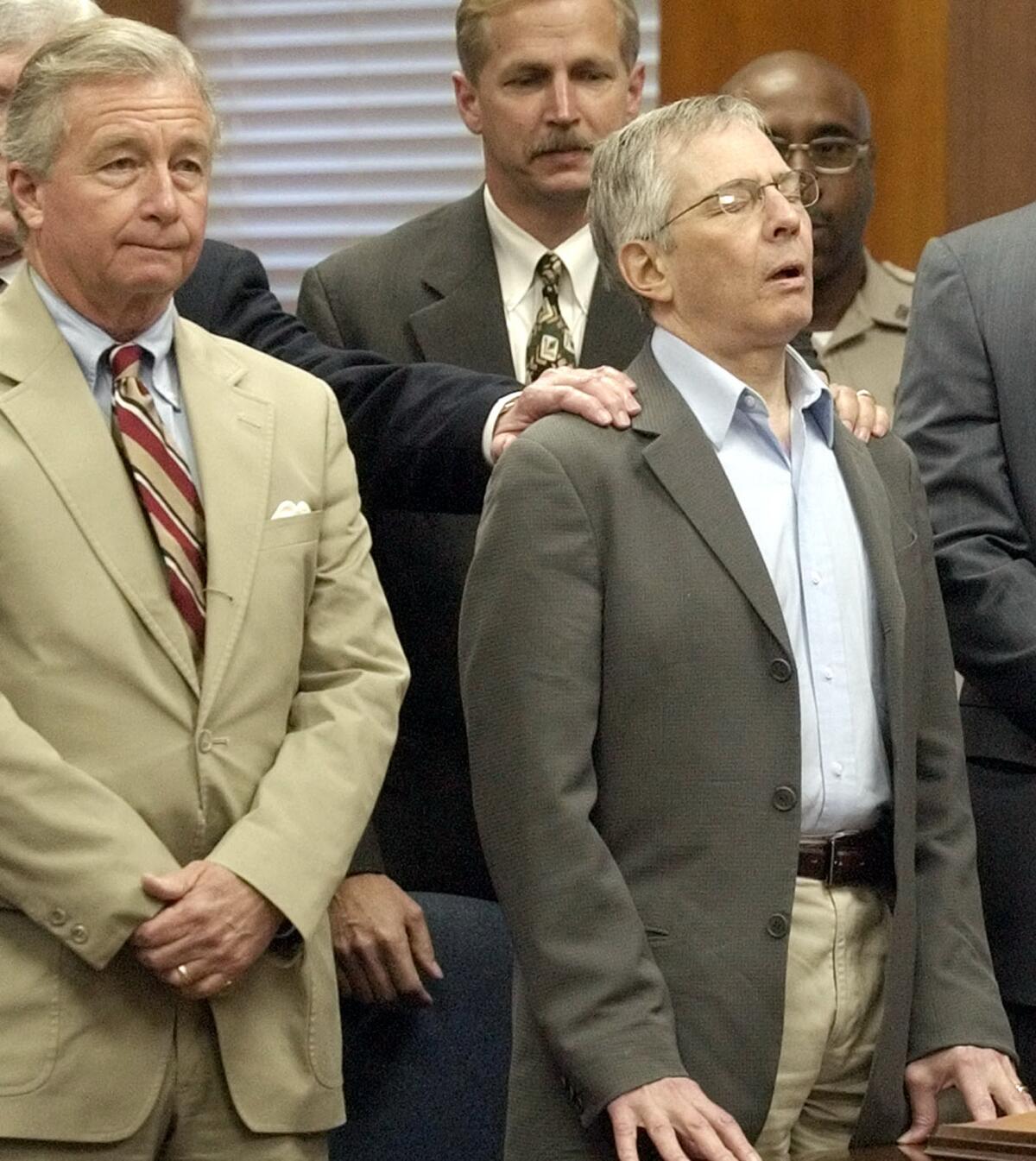 Standing with his attorneys, multi-millionaire murder defendant Robert Durst, right, reacts to a not guilty verdict on Nov. 11, 2003, in Galveston, Texas.