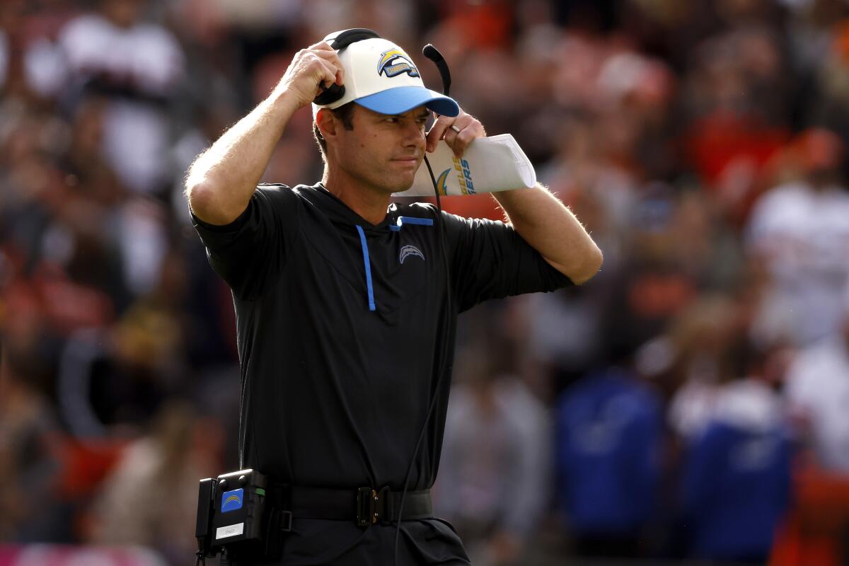 Chargers head coach Brandon Staley adjust his headset on the sideline.