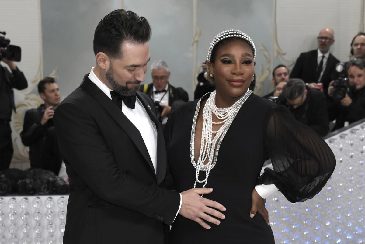 Alexis Ohanian rubs Serena Williams' belly on the Met Gala carpet. Both are dressed in black-and-white formal attire